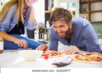 Young Couple Making Pizza In Kitchen Together