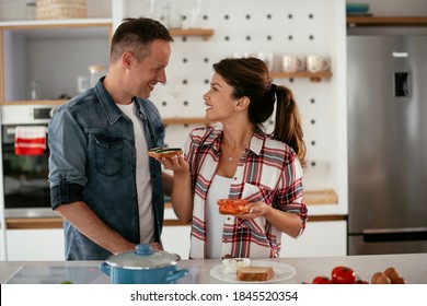 Young Couple Making Sandwich At Home. Loving Couple Enjoying In The Kitchen.