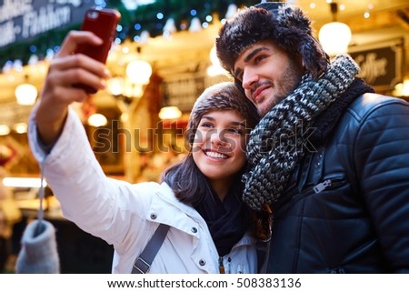 Young couple making selfie on christmas market, smiling happy.