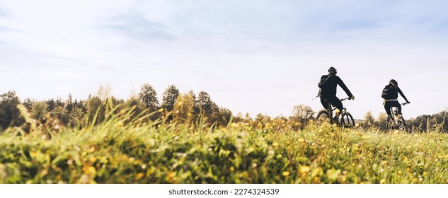 Young couple man and woman bicyclists with backpacks riding under sunset light at the early warm autumn time. Active sport people concept image	 - Powered by Shutterstock