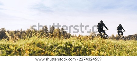 Young couple man and woman bicyclists with backpacks riding under sunset light at the early warm autumn time. Active sport people concept image	
