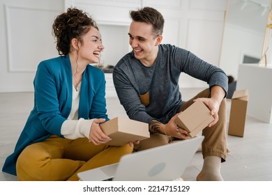 Young Couple Man And Woman Boyfriend And Girlfriend Or Husband And Wife Exchange Gifts At Home Giving Presents To Each Other And Opening Box Happy Smile Celebrate Valentine Holiday Or Birthday