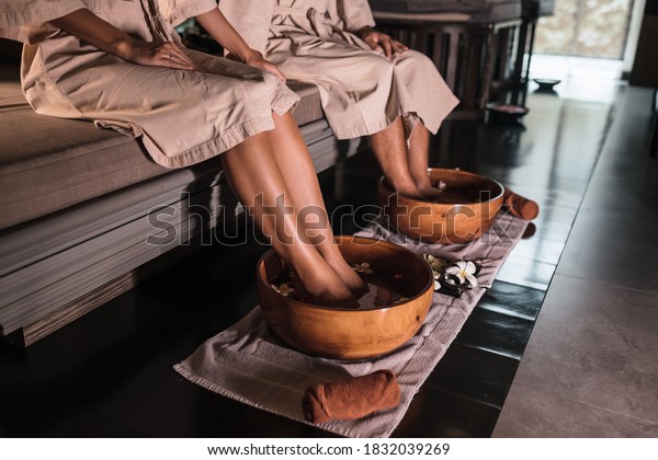 Young couple man and woman dipping their feet\
in a bowl, waiting for the spa staff to cleanse. Feet in a bowl of\
floral scented water at the spa\
center.