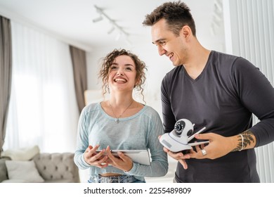 Young couple man and woman husband and wife or caucasian boyfriend and girlfriend setting up home surveillance security camera cctv protecting their home apartment bright room real people copy space - Shutterstock ID 2255489809