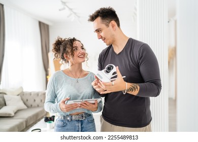 Young couple man and woman husband and wife or caucasian boyfriend and girlfriend setting up home surveillance security camera cctv protecting their home apartment bright room real people copy space - Shutterstock ID 2255489813