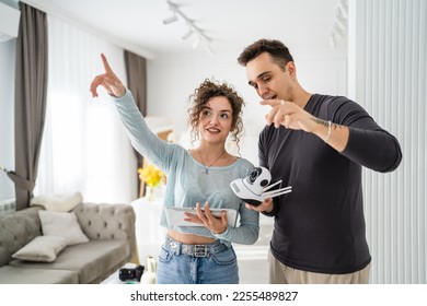Young couple man and woman husband and wife or caucasian boyfriend and girlfriend setting up home surveillance security camera cctv protecting their home apartment bright room real people copy space - Shutterstock ID 2255489827