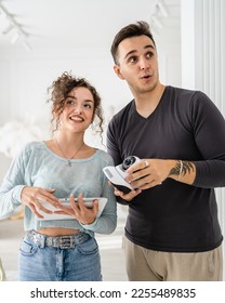 Young couple man and woman husband and wife or caucasian boyfriend and girlfriend setting up home surveillance security camera cctv protecting their home apartment bright room real people copy space - Shutterstock ID 2255489835