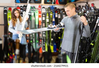 Young Couple Man And Woman Make Purchase Together, Choosing New Skis In A Sport Goods Store