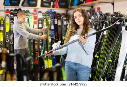 Young Couple Man And Woman Make Purchase Together, Choosing New Skis In A Sport Goods Store