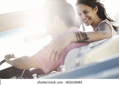 A Young Couple, Man And Woman In A Pale Blue Convertible On The Open Road