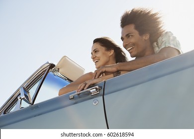 A Young Couple, Man And Woman In A Pale Blue Convertible On The Open Road