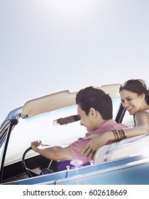 A Young Couple, Man And Woman In A Pale Blue Convertible On The Open Road