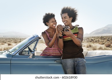 A young couple, man and woman in a pale blue convertible on the open road - Powered by Shutterstock