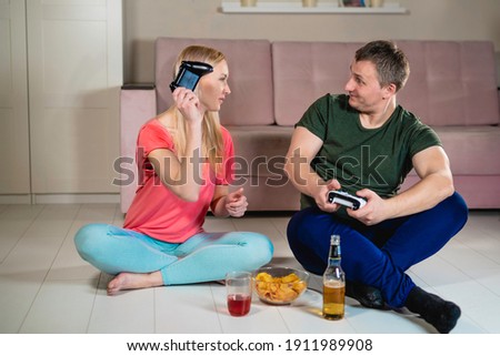 young couple, man with woman play video game. The girl lost and swings the joystick, the guy happily teases her