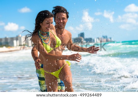 Young Couple Man and Woman Playing in Surf at Beach