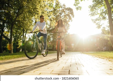 Young couple man and woman ride a bike in the park in the autumn season on a background of sunset. Cycling on the weekend with a friend. - Powered by Shutterstock