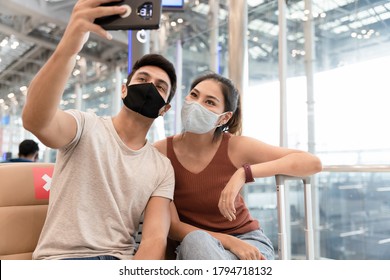 Young Couple Man And Woman Wearing Face Mask Selfie By Smartphone While Waiting To On Board In The Airport. Worry Free And Travel Insurance Concept.