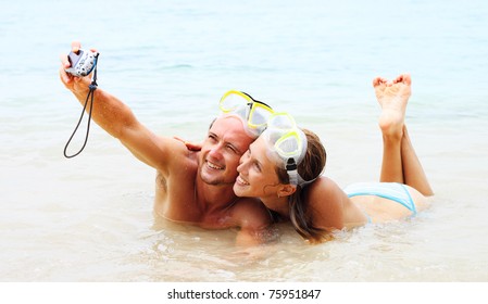 Young couple in the masks making photo of themselves in the sea - Powered by Shutterstock