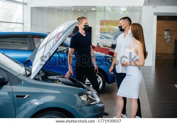 Young couple in masks
selects a new vehicle and consult with a representative of the
dealership in the period of the pandemic. Car sales, and life
during the pandemic