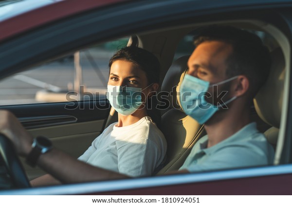 The young
couple in masks are sitting in the
car