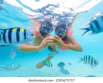 A young couple of men and a woman on a snorkeling trip at Samaesan Thailand. dive underwater with Nemo fishes in the coral reef sea pool. couple swim activity on a summer beach holiday 