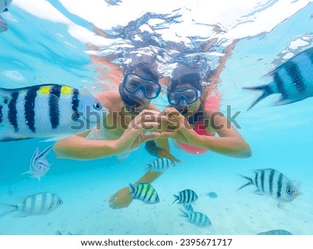 A young couple of men and a woman on a snorkeling trip at Samaesan Thailand. dive underwater with Nemo fishes in the coral reef sea pool. couple swim activity on a summer beach holiday 