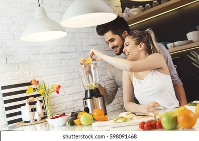 Young couple mixing fruit in a food processor, making a smoothie - Powered by Shutterstock