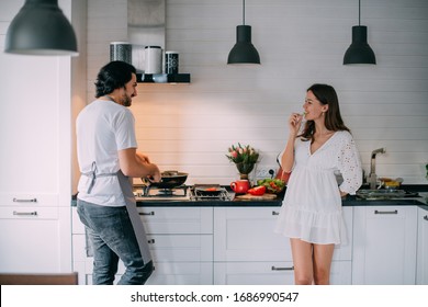  Young Couple In The Morning In The Kitchen At Home. A Man Cooks A Woman A Festive Breakfast On March 8 In A Beautiful Stylish Kitchen.