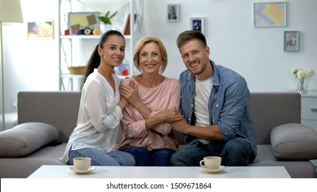 Young Couple And Mother In Law Holding Hands, Smiling At Camera, Happy Together