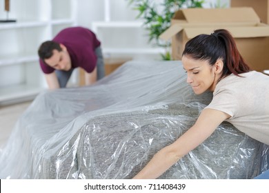 Young Couple Moving Couch To Their New Apartment