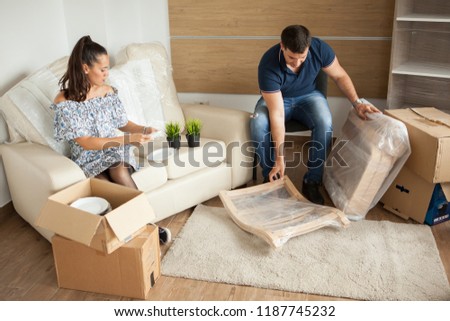 Young couple Moving in new home and unpacking carboard boxes.Almost done moving in.