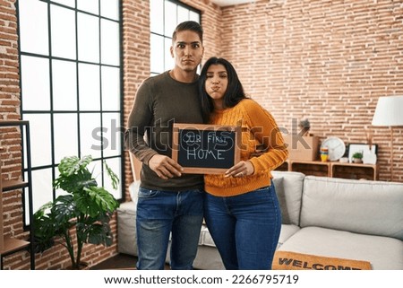 Young couple moving to a new home puffing cheeks with funny face. mouth inflated with air, catching air. 