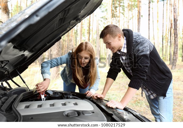 Young couple near\
damaged car in forest