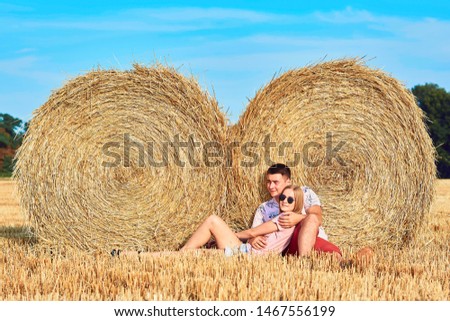 Young couple near a hay bale in the countryside