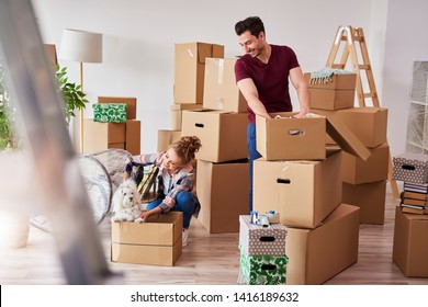 Young Couple In New Apartment With Small Dog 