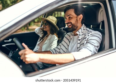 Young couple in a new car. A man driving a car with his girlfriend and having fun. Buying and renting a car. Travel, tourism, recreation. - Shutterstock ID 2051439191