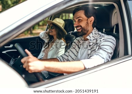 Young couple in a new car. A man driving a car with his girlfriend and having fun. Buying and renting a car. Travel, tourism, recreation.