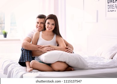 Young couple on bed with soft pillows at home