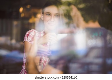 Young Couple On First Date Drinking Coffee, Shot Through Window Glass