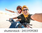 Young couple on a off road adventure excursion outside - Joyful tourists taking selfie with smart mobile phone in the desert - Tourism tour activities, transportation and summertime holidays concept