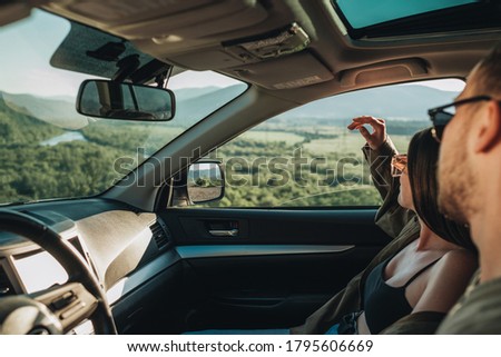 Young Couple on Road Trip, Man Diving Car with Woman Sitting on Passenger Seat