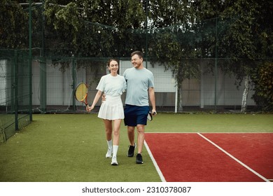 Young couple on tennis court. Two tennis players are smiling and walking around the court and talking - Powered by Shutterstock