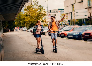 Young Couple On Vacation Having Fun Driving Electric Scooter Through The City.	