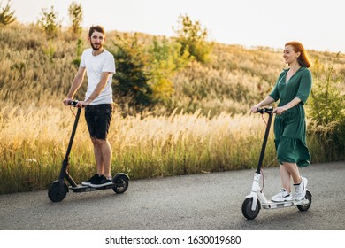 Young couple on vacation having fun driving electric scooter on the road in the countryside. Content technologies. Copy space.