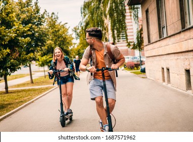 Young couple on vacation having fun driving electric scooter through the city. - Shutterstock ID 1687571962