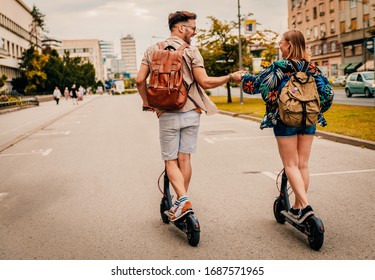 Young couple on vacation having fun driving electric scooter through the city. - Shutterstock ID 1687571965