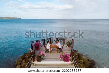 young couple on vacation in Saint Lucia relaxing on a wooden pier in the ocean, luxury holiday Saint Lucia Caribbean, men and woman on vacation at the tropical Island of Saint Lucia Caribbean. 