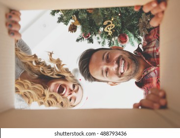 Young couple opening a Christmas present, view from inside of the box - Powered by Shutterstock