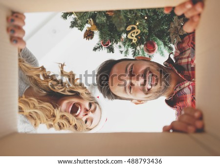 Young couple opening a Christmas present, view from inside of the box