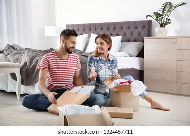 Young Couple Opening Parcels In Bedroom At Home